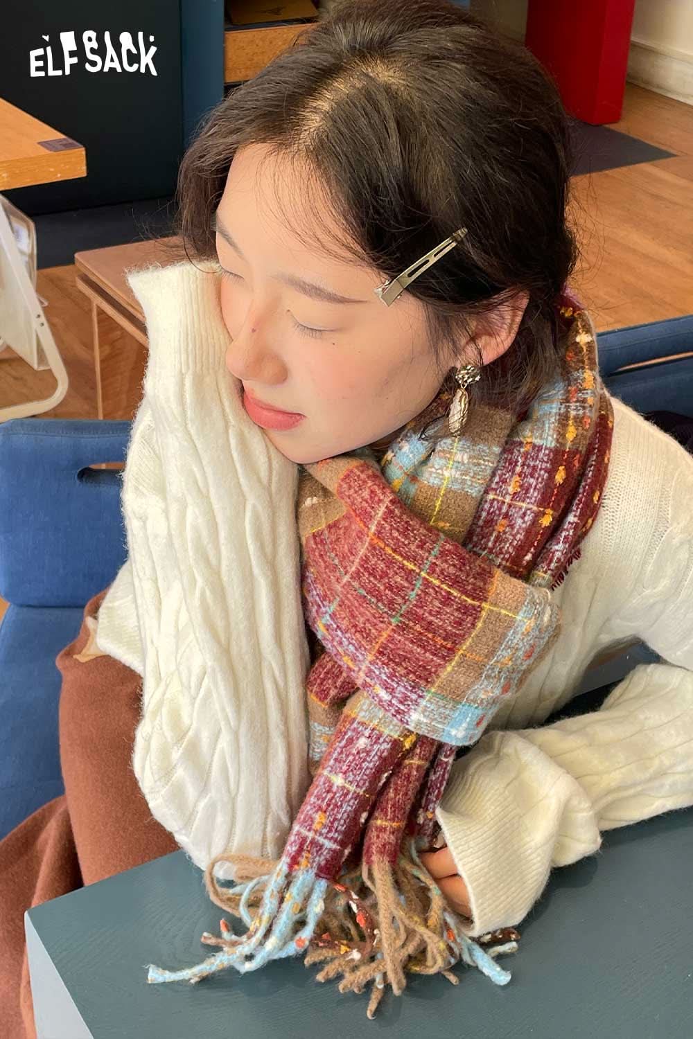 
                  
                    Cozy ELFSACK vintage plaid wool scarf wrapped around a stylish model indoors
                  
                