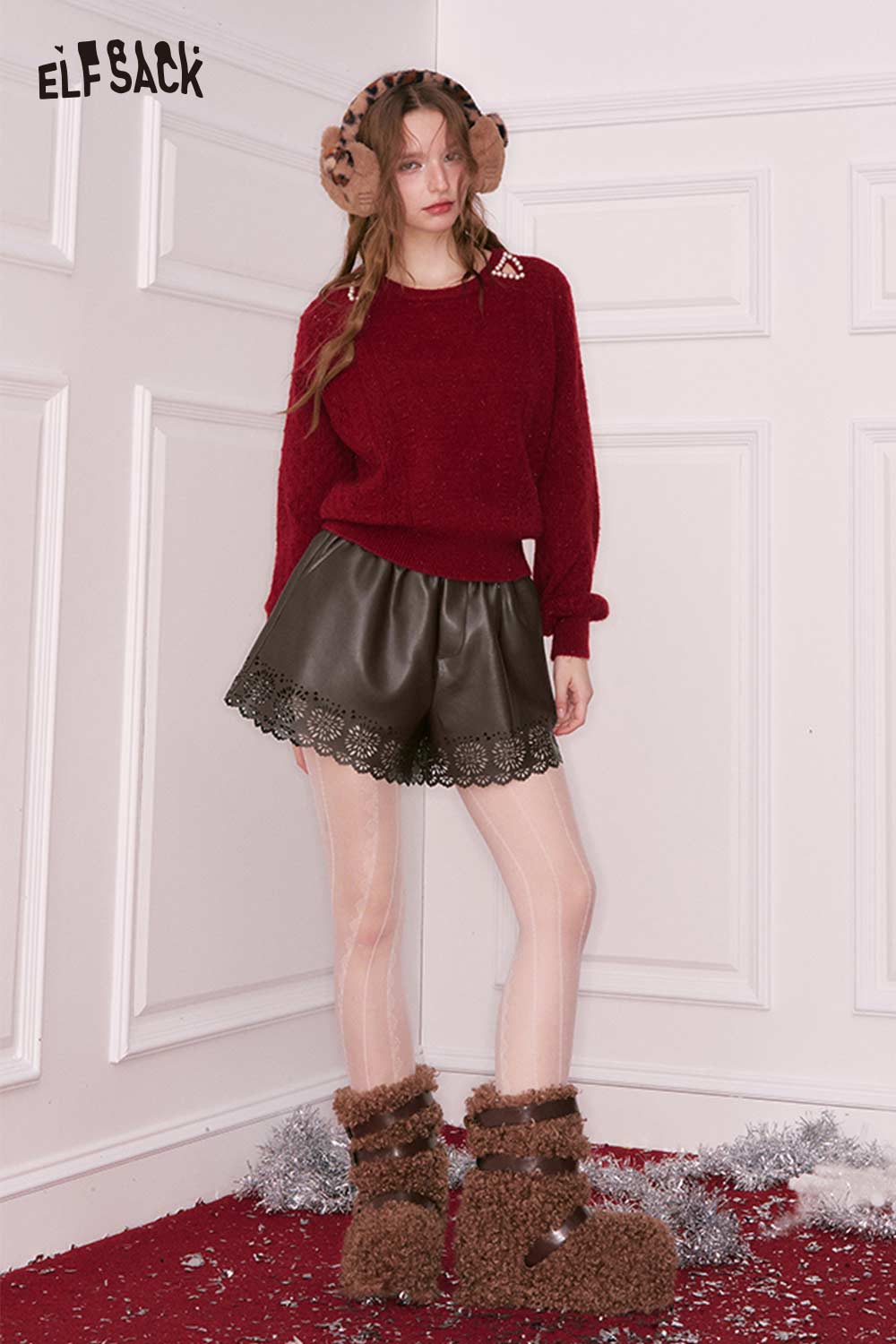 Stylish women's PU leather shorts with lace trim, paired with a cozy red sweater and winter accessories