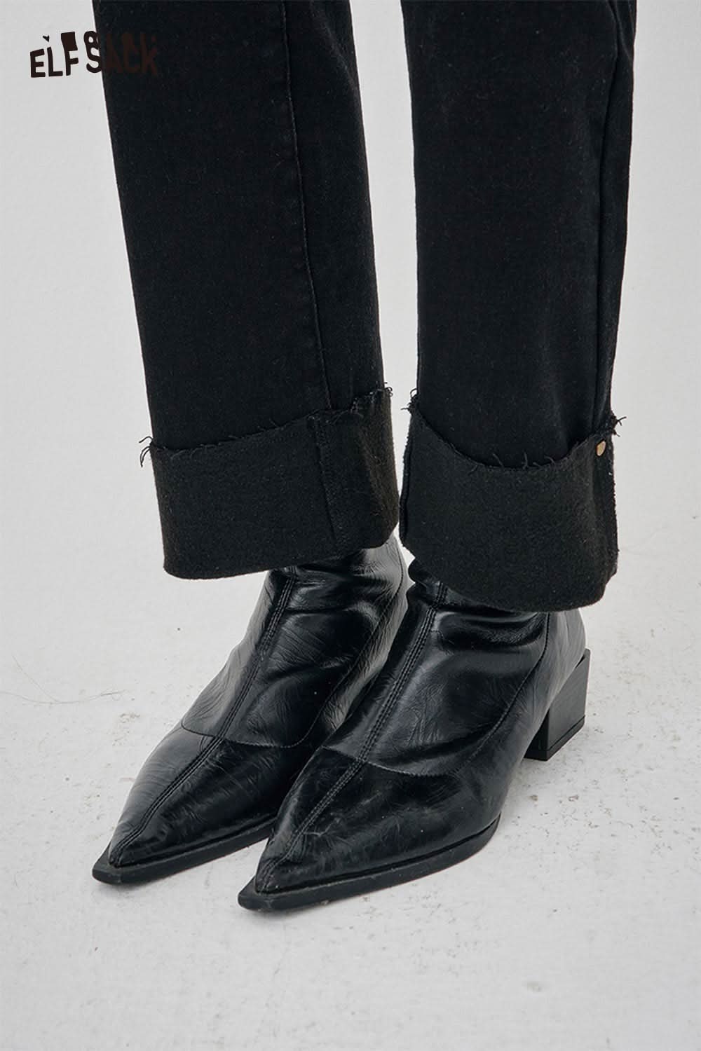 Close-up of women's black denim straight leg pants paired with stylish black pointed toe boots