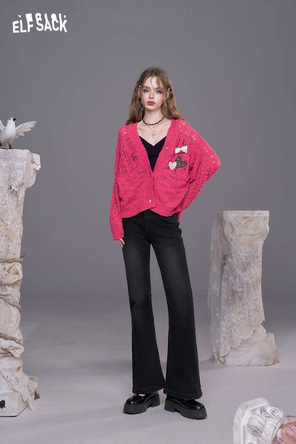 Model wearing ELFSACK women's bootcut stretch denim jeans paired with a pink cardigan and stylish accessories