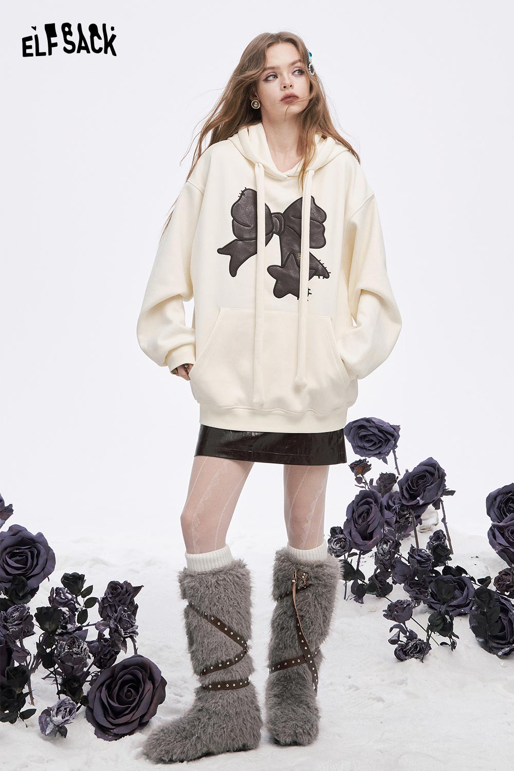 ELFSACK women's casual graphic hoodie in cream with bow design, styled with a skirt and fuzzy boots