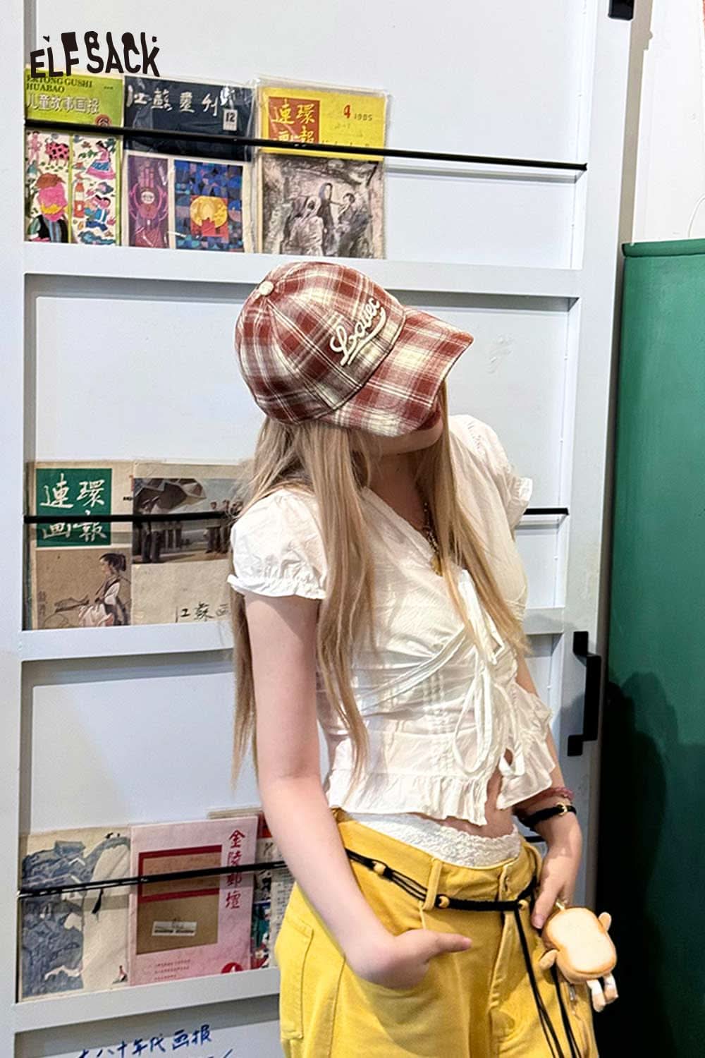 Trendy women's checkered baseball cap in red, styled with a white blouse and yellow pants