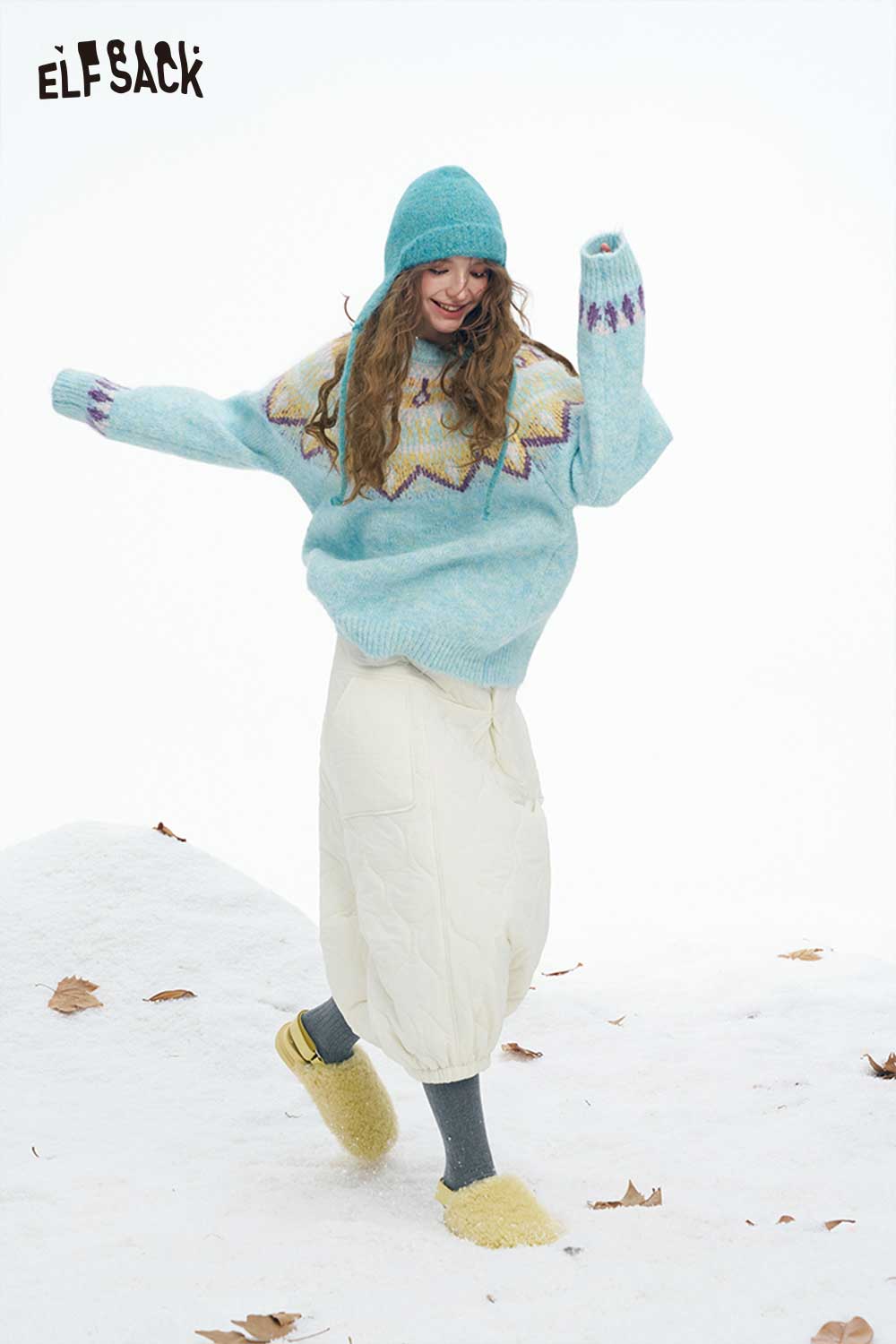 ELFSACK women's down half skirt paired with cozy oversized sweater and beanie in wintery outdoor setting