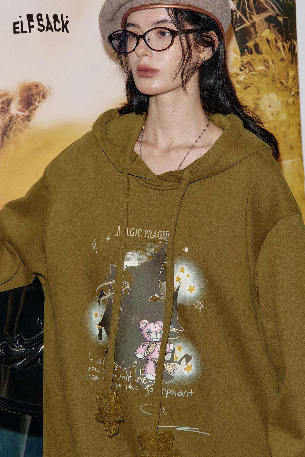 ELFSACK women's graphic print hoodie in olive green featuring a playful bear design with stars