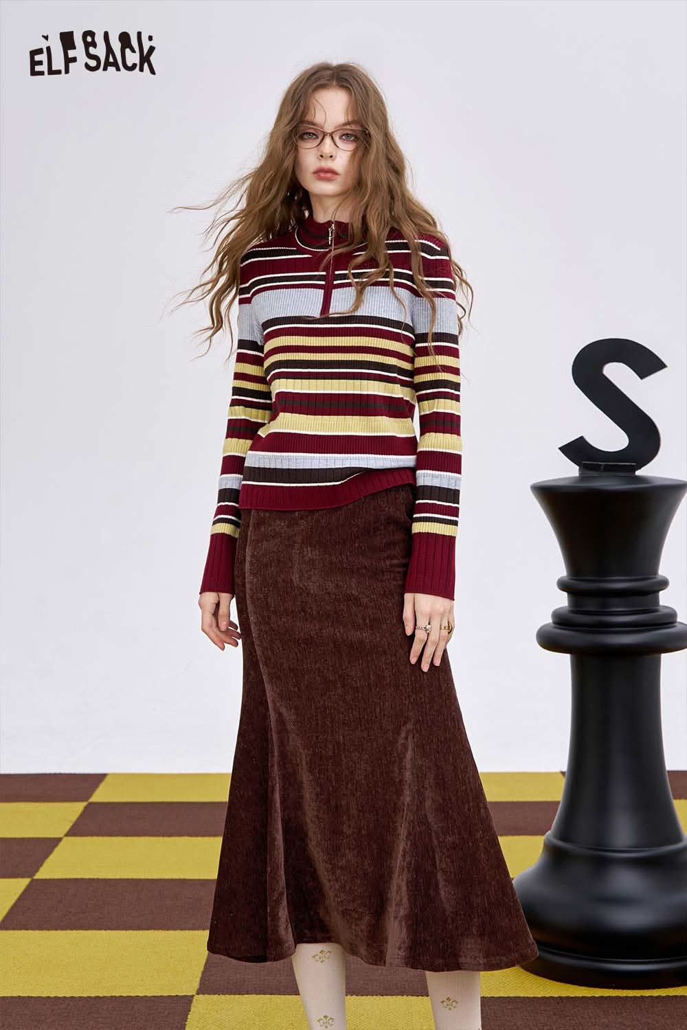 ELFSACK women's half zip knit sweater in striped design paired with a brown skirt on a colorful backdrop