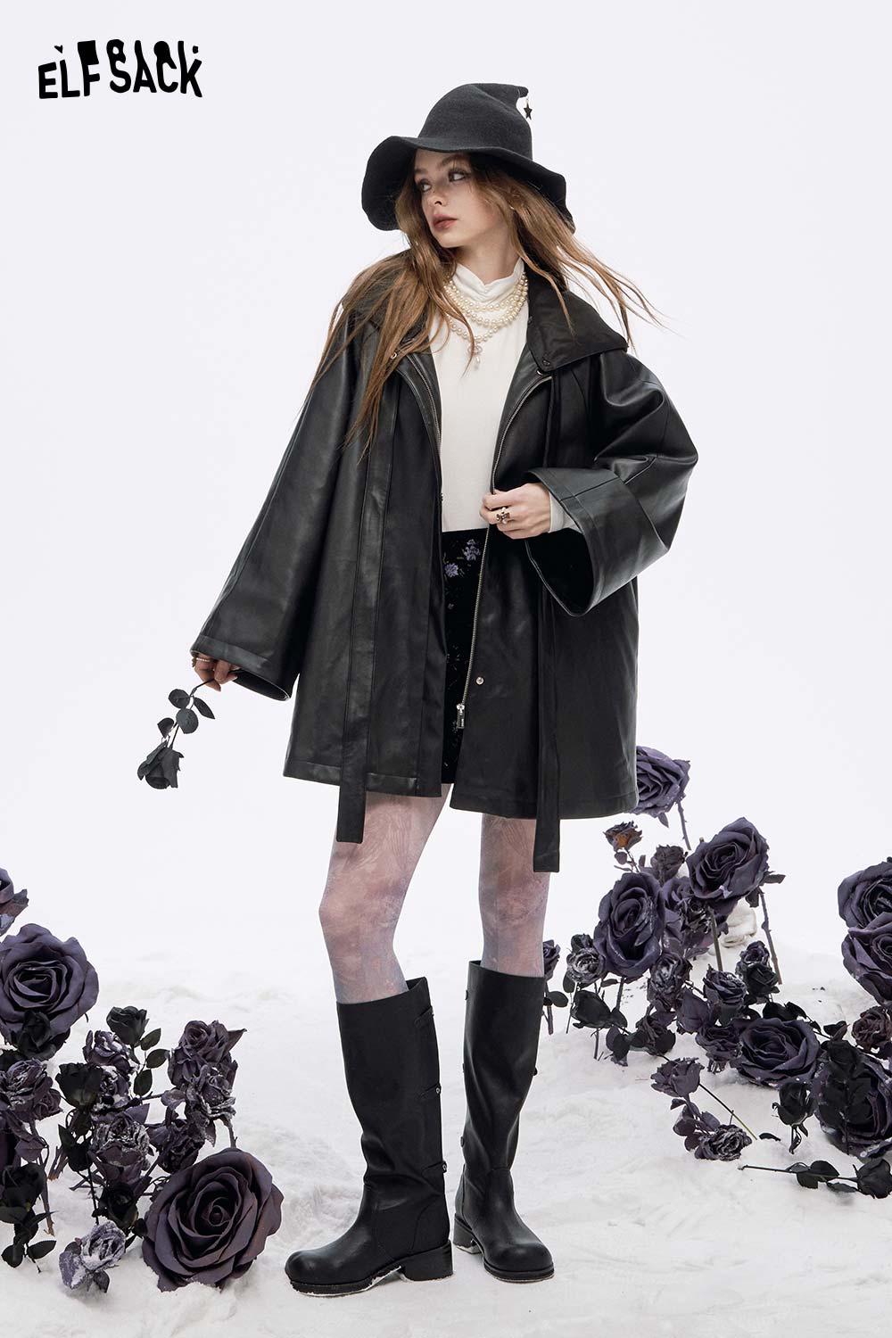 Stylish model wearing a women's high neck pearl t-shirt under a black leather jacket outdoors