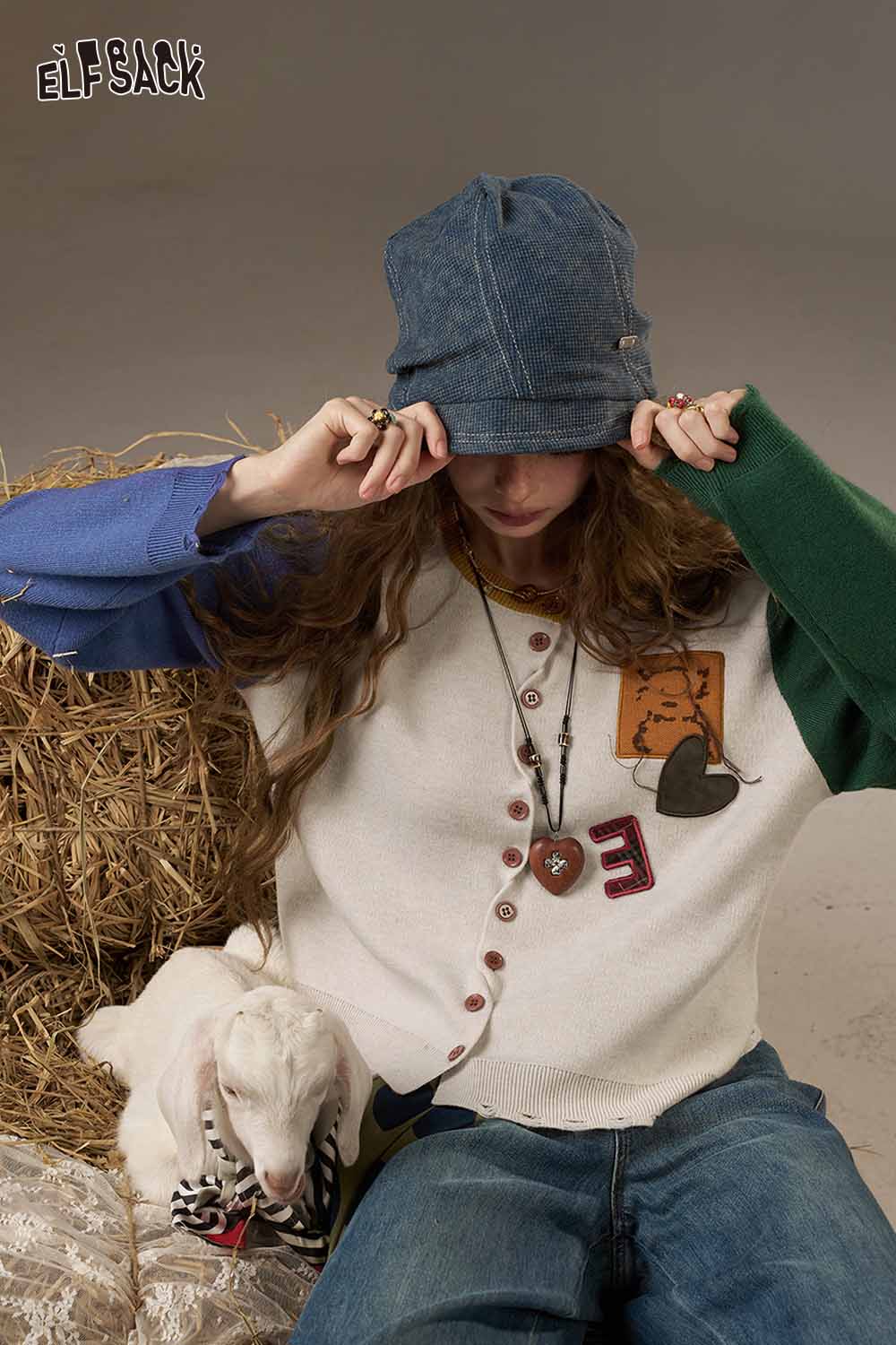 ELFSACK women's knitted jacket featuring colorful patches and button details worn with denim look cap