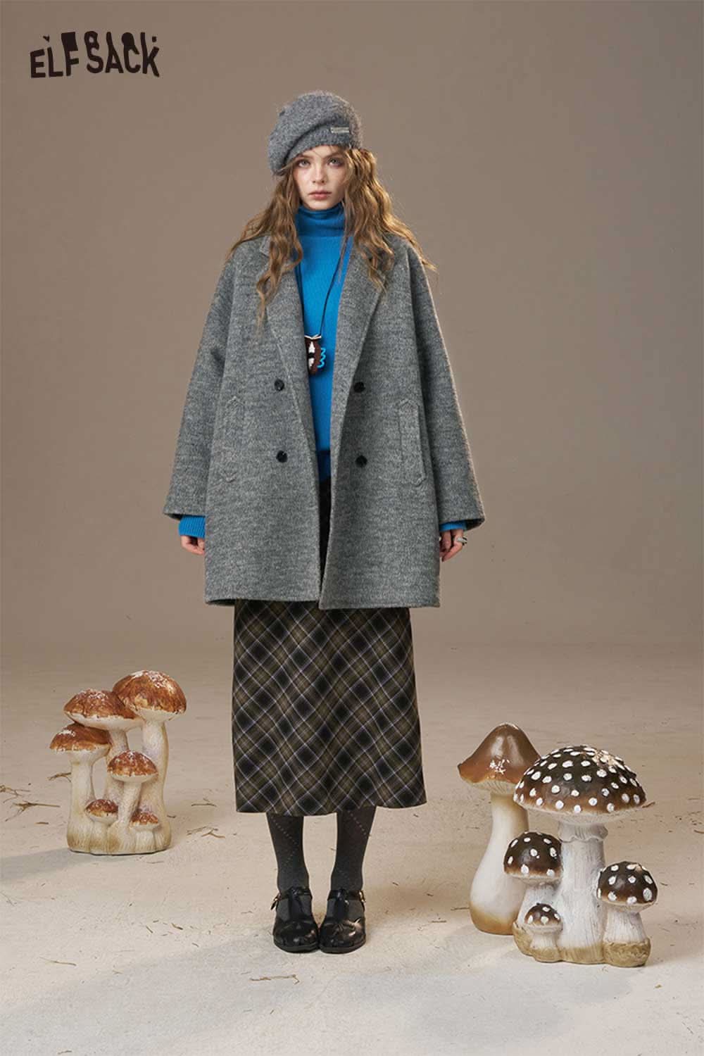 ELFSACK women's oversize wool blend coat in gray, styled with a blue turtleneck and a hat, surrounded by whimsical mushrooms