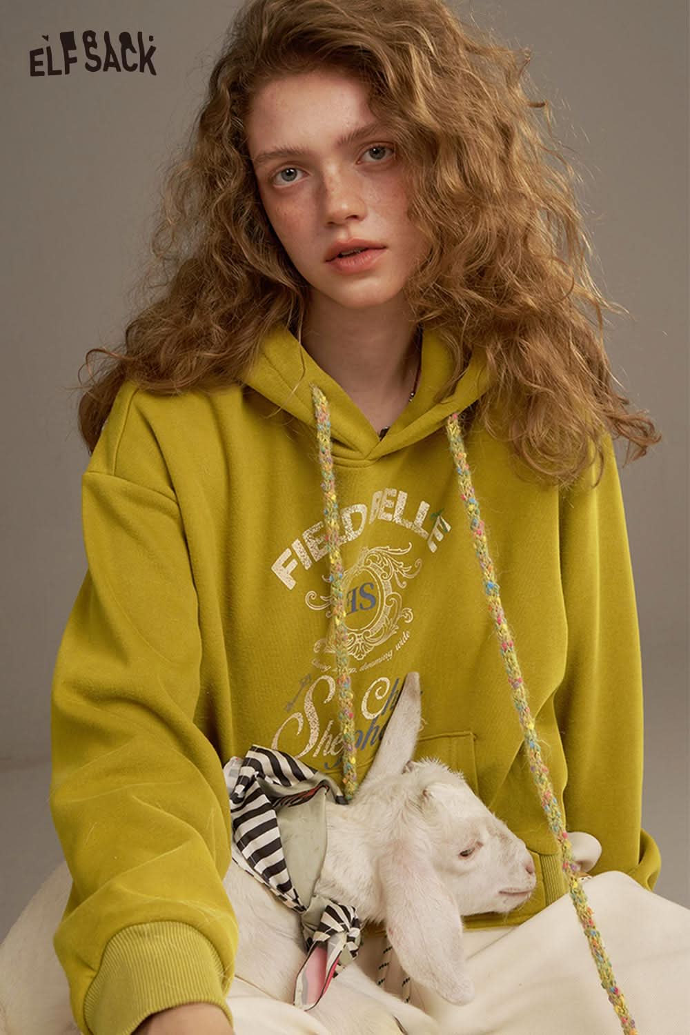 ELFSACK women's oversized print hoodie in mustard yellow with playful graphic design and adjustable drawstrings