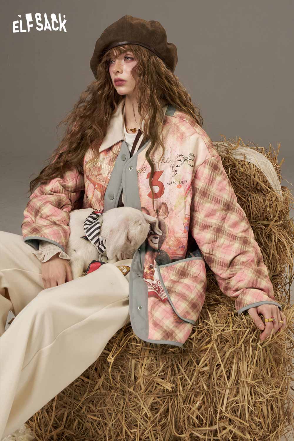 ELFSACK women's printed cotton jacket in a colorful design, styled with a hat and sitting with a pet on a hay bale