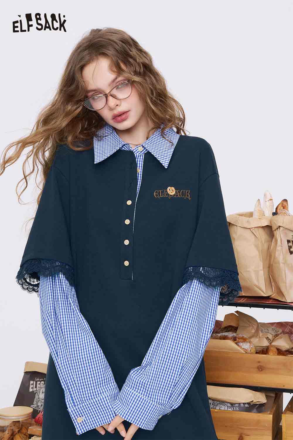 ELFSACK model wearing navy college style knit dress layered over blue gingham shirt with lace trim