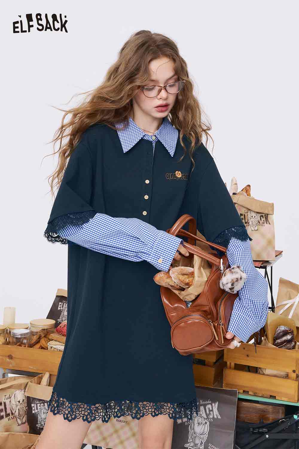 ELFSACK model wearing navy college style knit dress with gingham collar lace hem holding brown leather bag with baguette