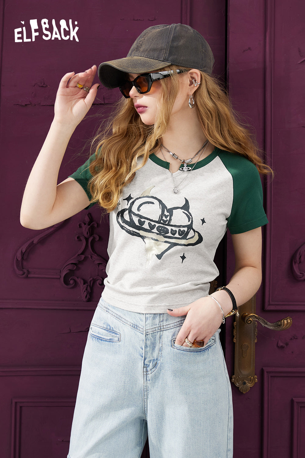 ELFSACK Y2K Heart Graphic T-shirt with green sleeves worn by woman with sunglasses and cap