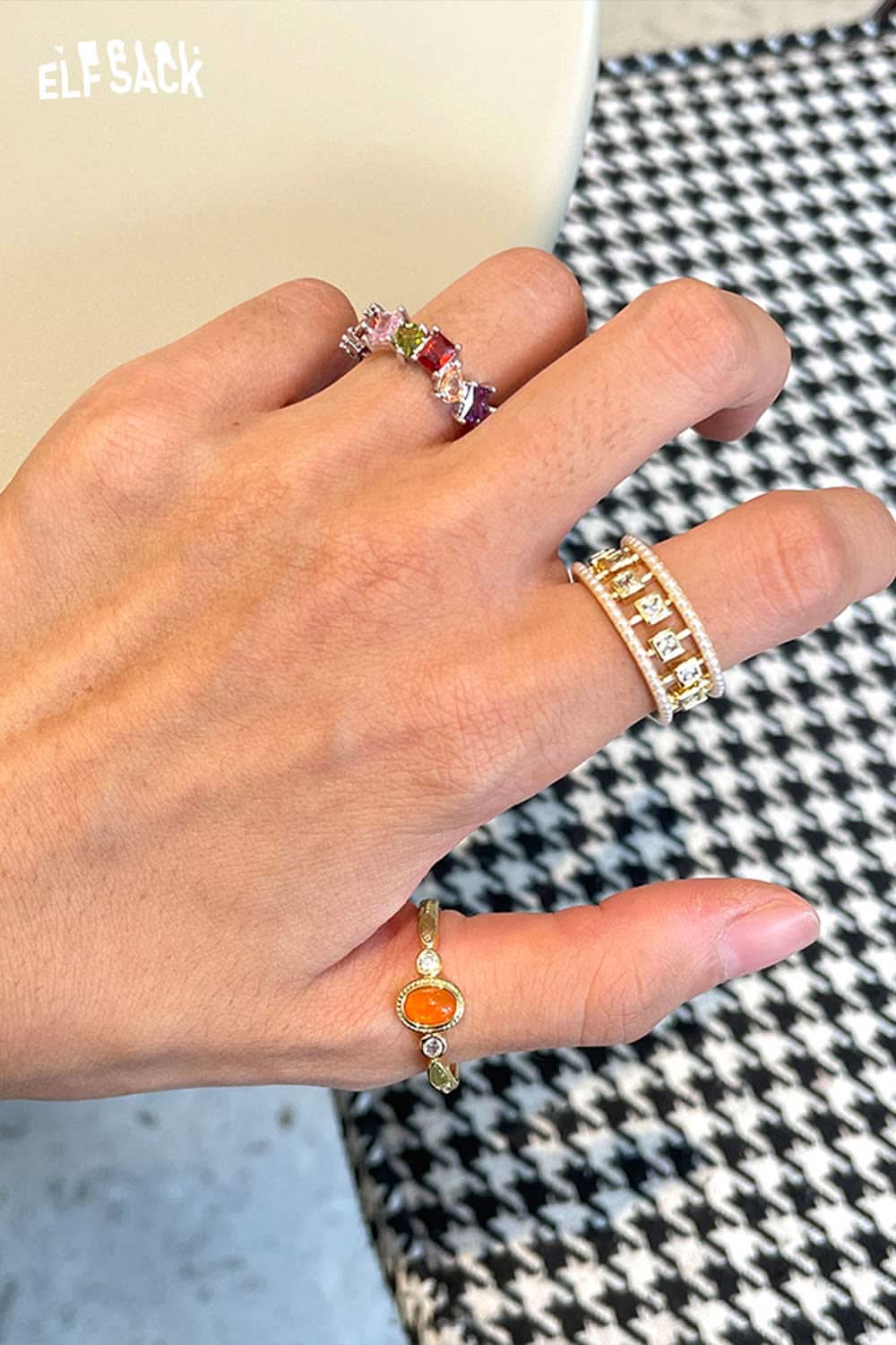 ELFSACK zirconia gemstone copper ring displayed among colorful gemstone rings on a hand