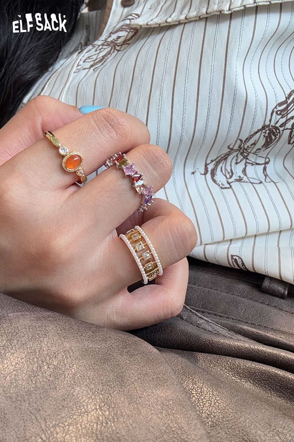 ELFSACK zirconia gemstone copper ring worn with other stylish rings on a hand